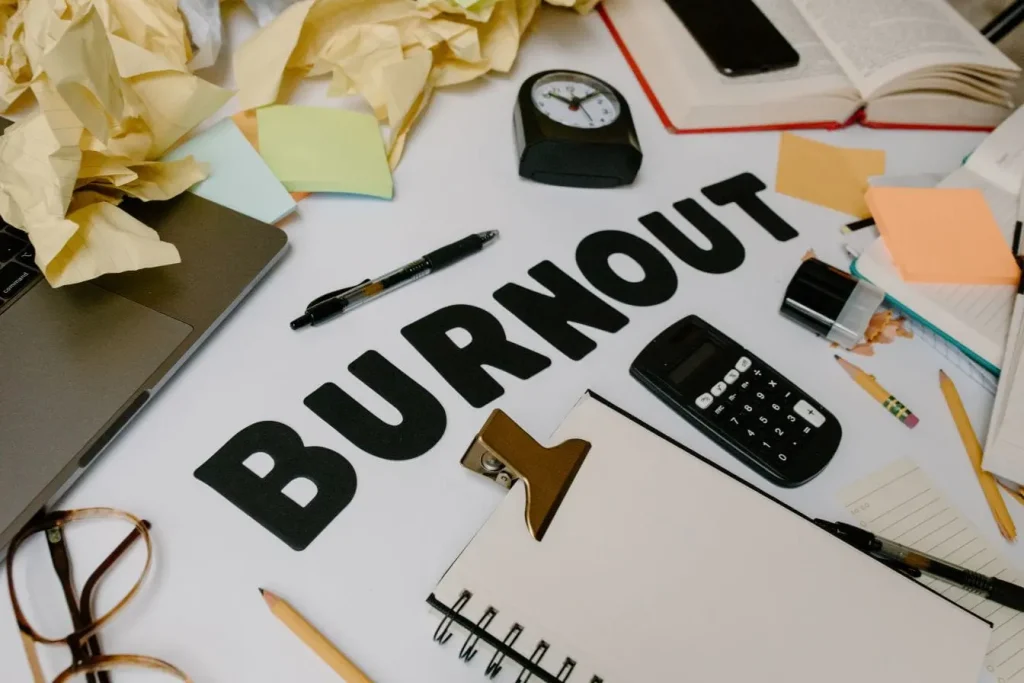 Bureau rempli d’objets divers, mot burnout au centre, image qui traduit la fatigue mentale et physique.