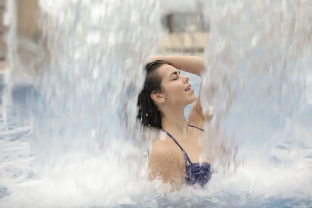 Personne debout sous cascade d’eau froide, image illustrant les effets revitalisants de la cryothérapie.