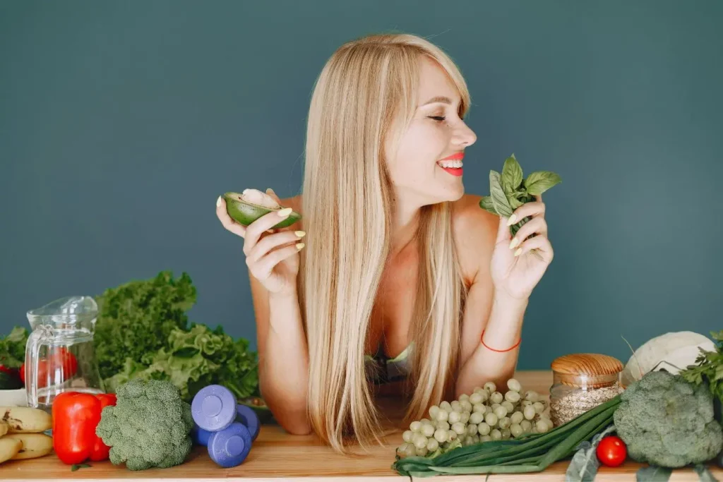 Personne tenant avocat et légumes verts, image qui illustre l’importance d’une alimentation saine pour limiter l’acné adulte.