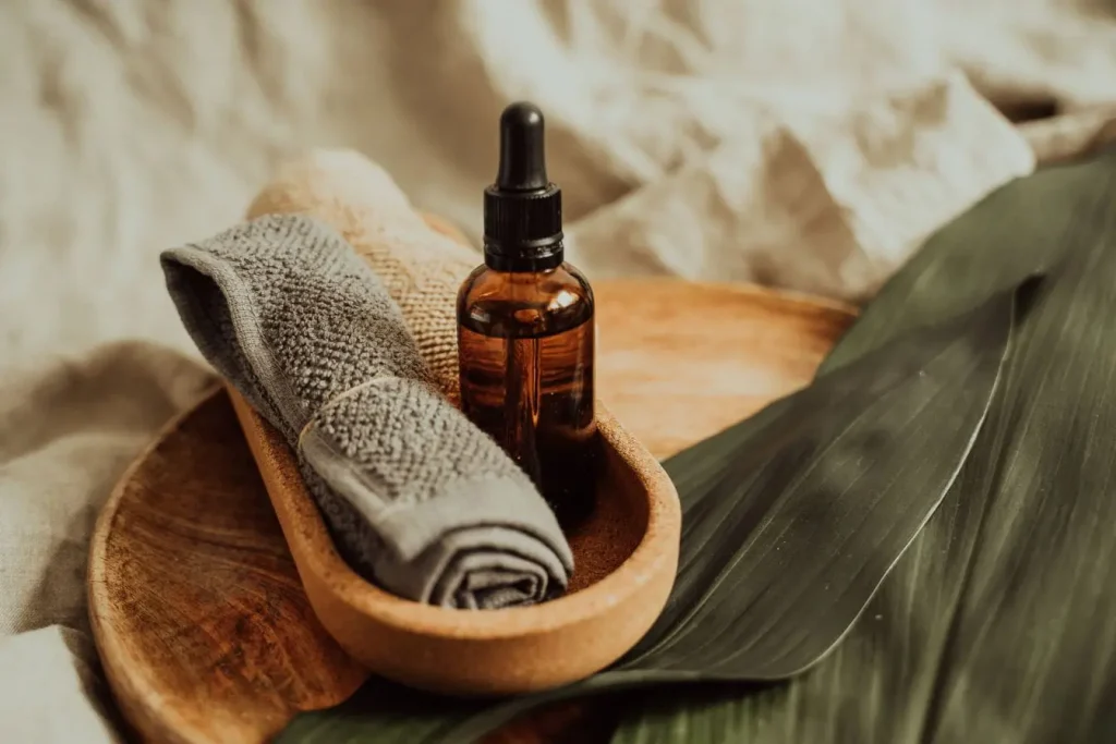 Petit flacon ambré avec pipette posé dans bol en bois, image qui illustre l’aromathérapie pour débutant et les bienfaits des huiles essentielles.