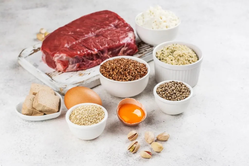Assortiment de viandes, œufs et graines disposés sur table claire, reflet d’une alimentation adaptée pour soulager les symptômes de la fibromyalgie.