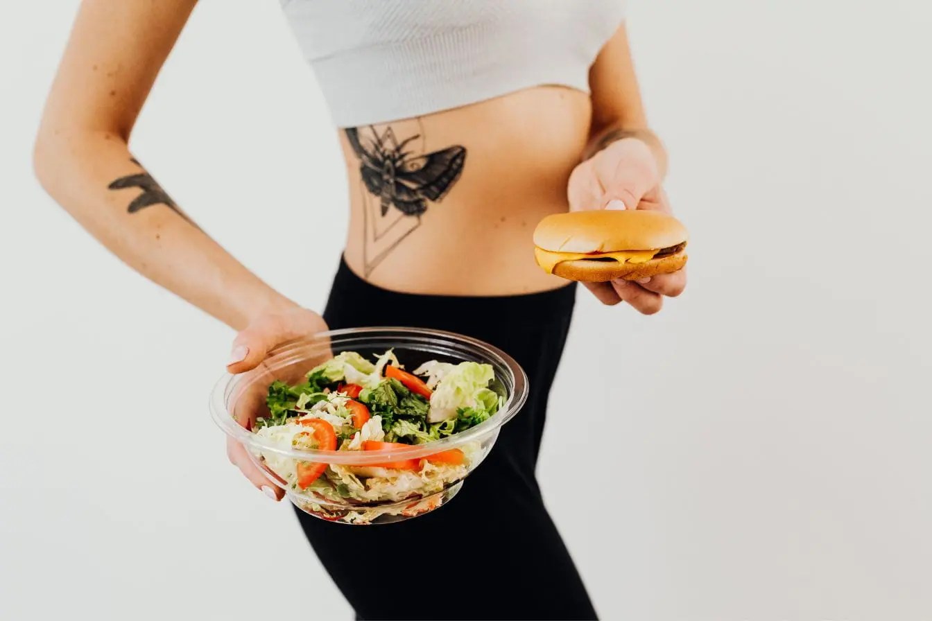 flexible dieting Personne tenant salade et burger, image qui illustre l’équilibre du flexible dieting et la logique IIFYM.