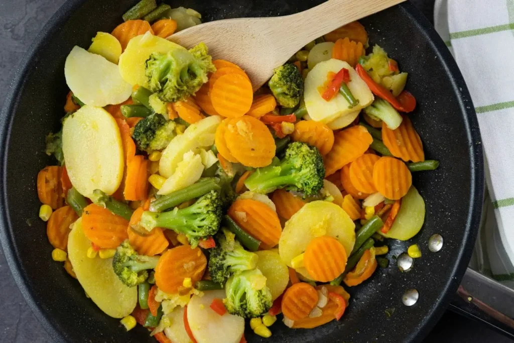 Carottes, brocolis et haricots verts mijotés ensemble, reflet du dilemme entre manger cru ou cuit pour garder les vitamines.