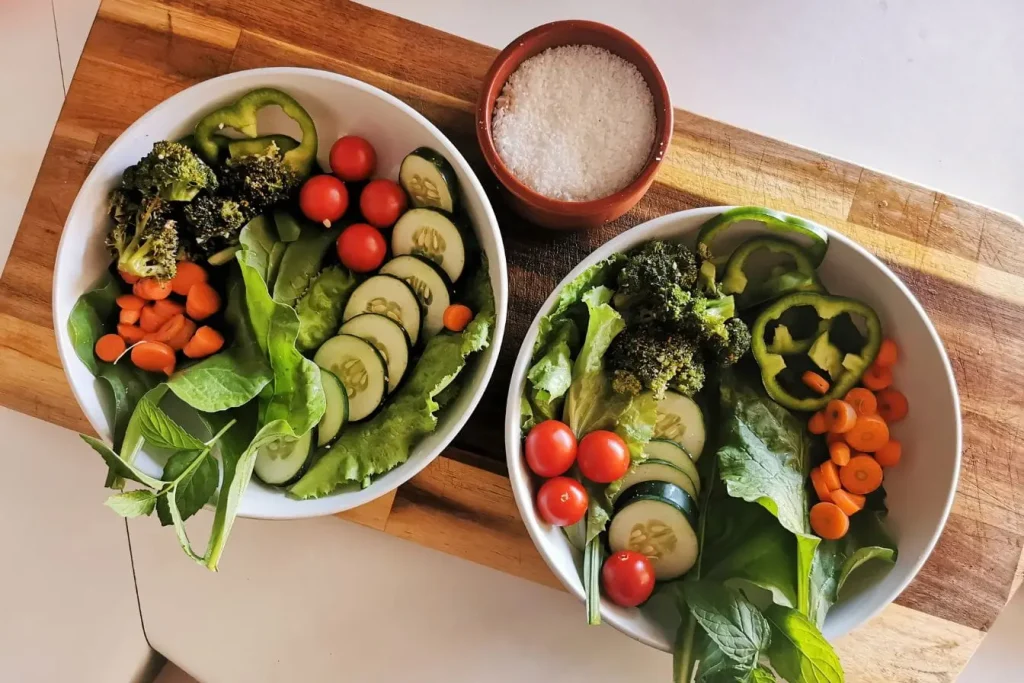 Deux bols remplis de légumes frais colorés sur planche en bois, image qui illustre les aliments naturels pouvant stimuler la thermogenèse et le métabolisme.