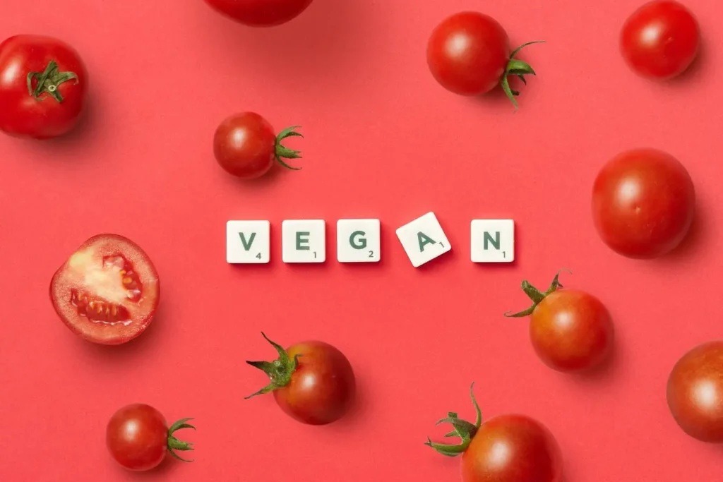 Tomates entières et tranches sur fond rouge avec mot VEGAN, reflet du risque de carence en vitamine B12 chez les végétaliens.