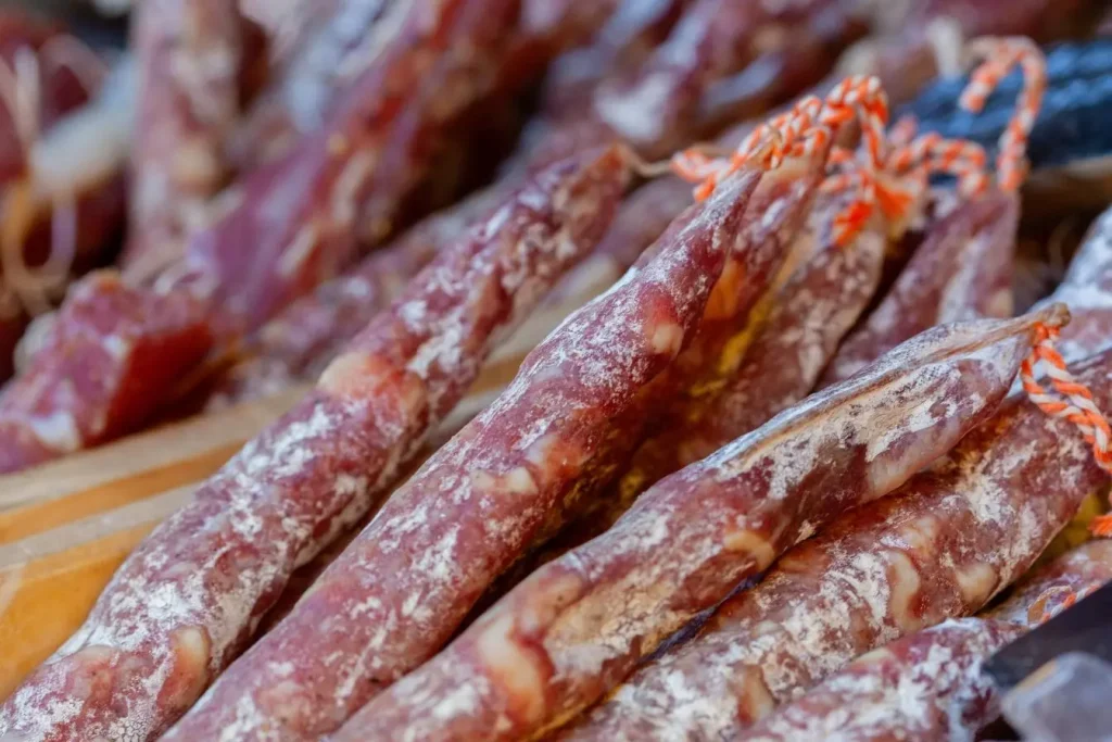 Saucisses sèches alignées avec surface poudreuse, image représentative des dangers des mycotoxines.