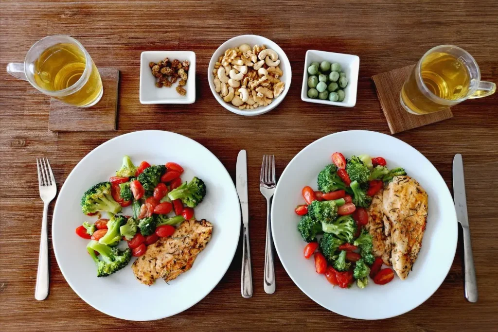 Table en bois avec repas équilibré poulet, brocoli et tomates, image qui illustre la logique IIFYM et flexible dieting.