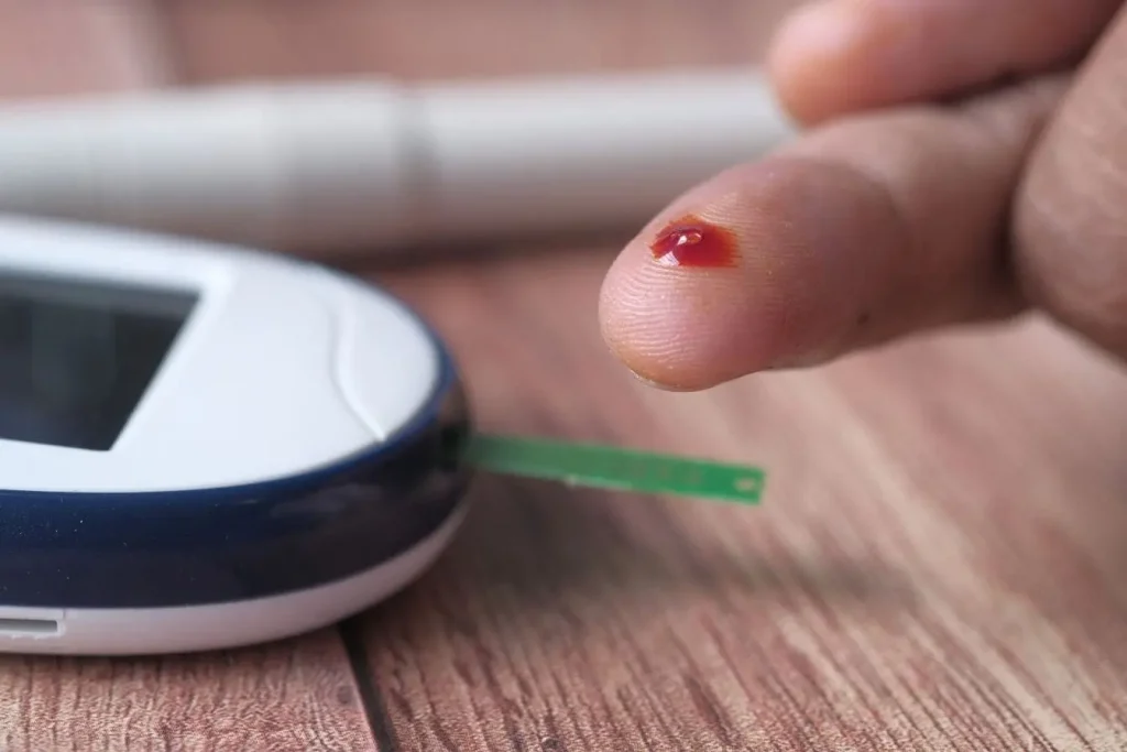 Une goutte de sang sur un doigt avant le test de glycemie illustre l'importance de la prevention du diabète de type 2 et du suivi médical régulier.