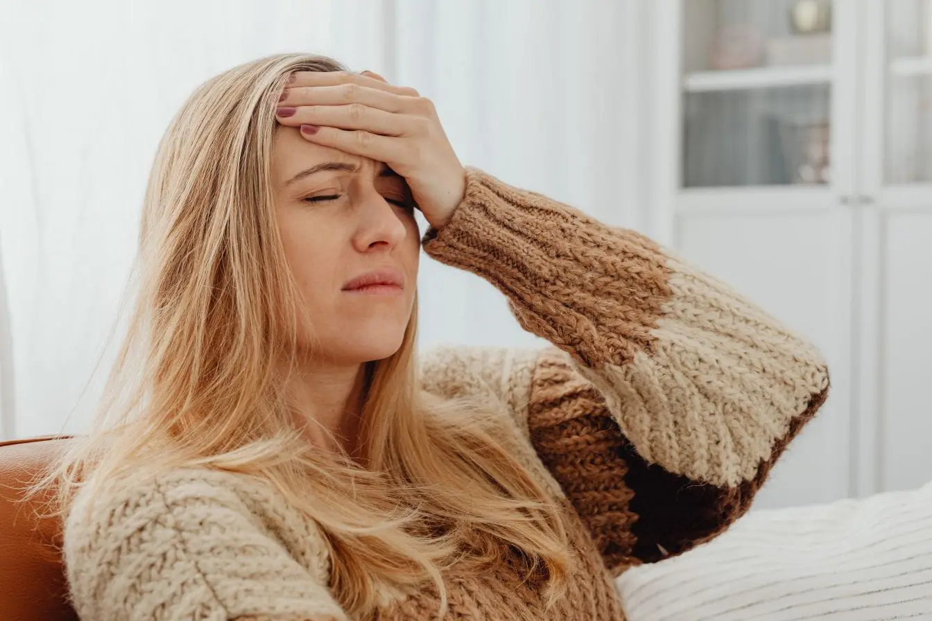 Migraine Personne assise avec main sur front et yeux fermés, reflet d’une migraine liée aux déclencheurs alimentaires.