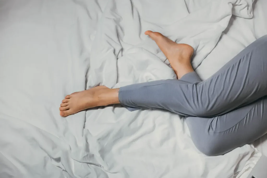 Gros plan sur pieds nus reposant sur draps blancs, reflet des crampes nocturnes et comment les expliquer.