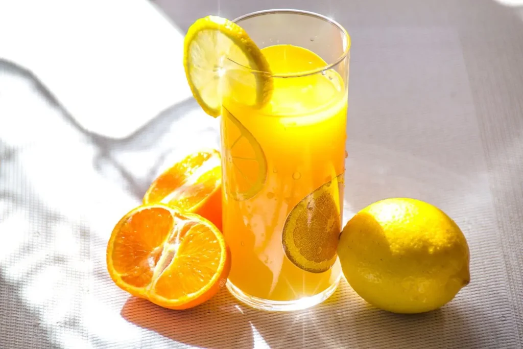Verre de jus orange garni de rondelles de citron et orange, reflet des meilleures sources alimentaires de vitamine E.