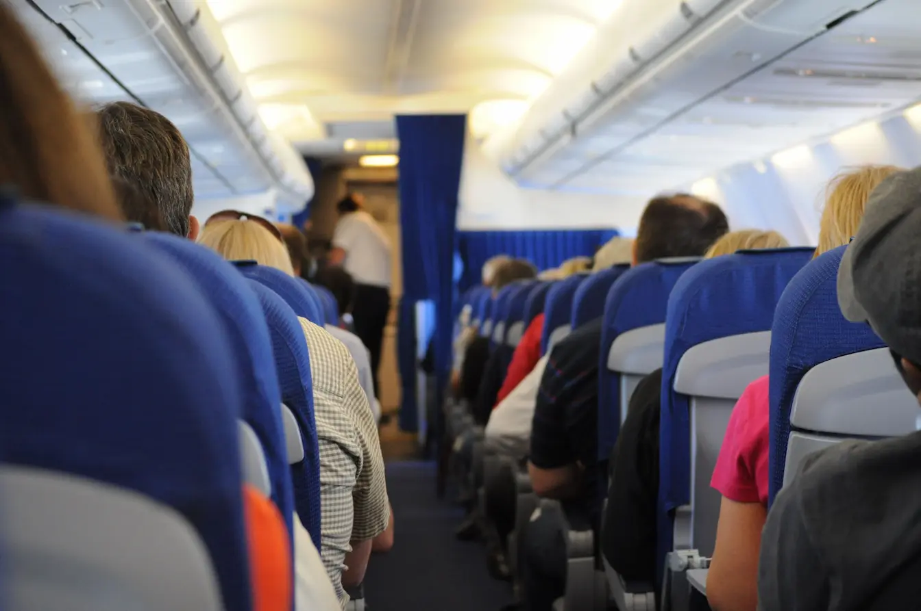 Vue intérieure d’un avion avec passagers assis, reflet des causes des jambes qui gonflent en avion et solutions pour les prévenir.