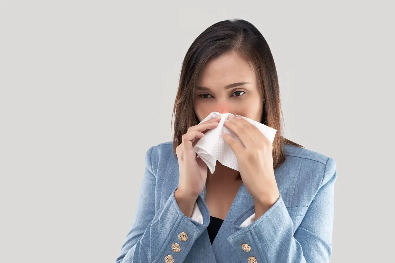 allergie saisonnière Main tenant mouchoir contre nez rouge, illustration typique des symptômes d’allergie saisonnière.