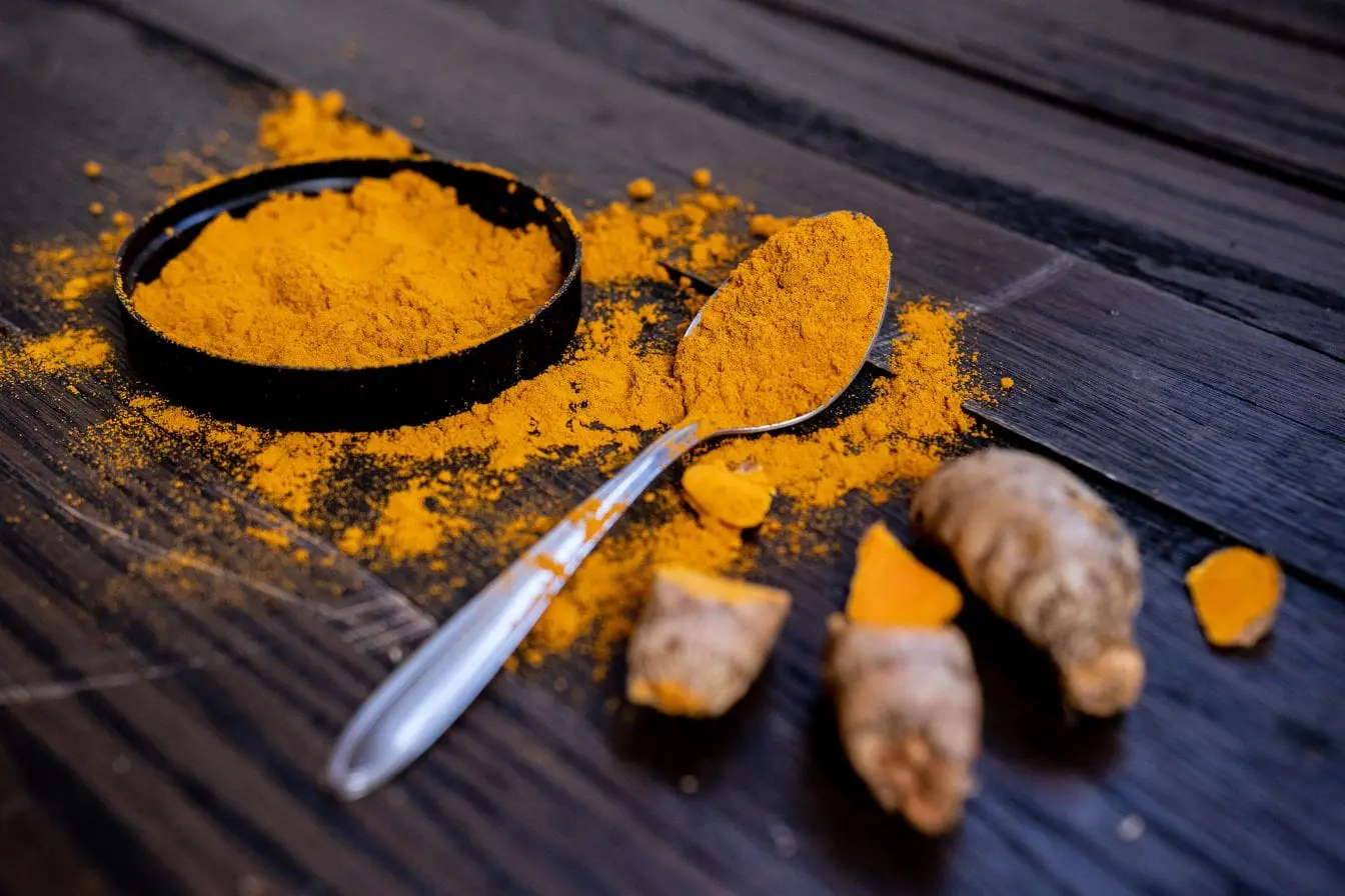 Gros plan sur poudre jaune éclatante et racines de curcuma, reflet des bienfaits naturels de cette épice aux vertus santé reconnues.