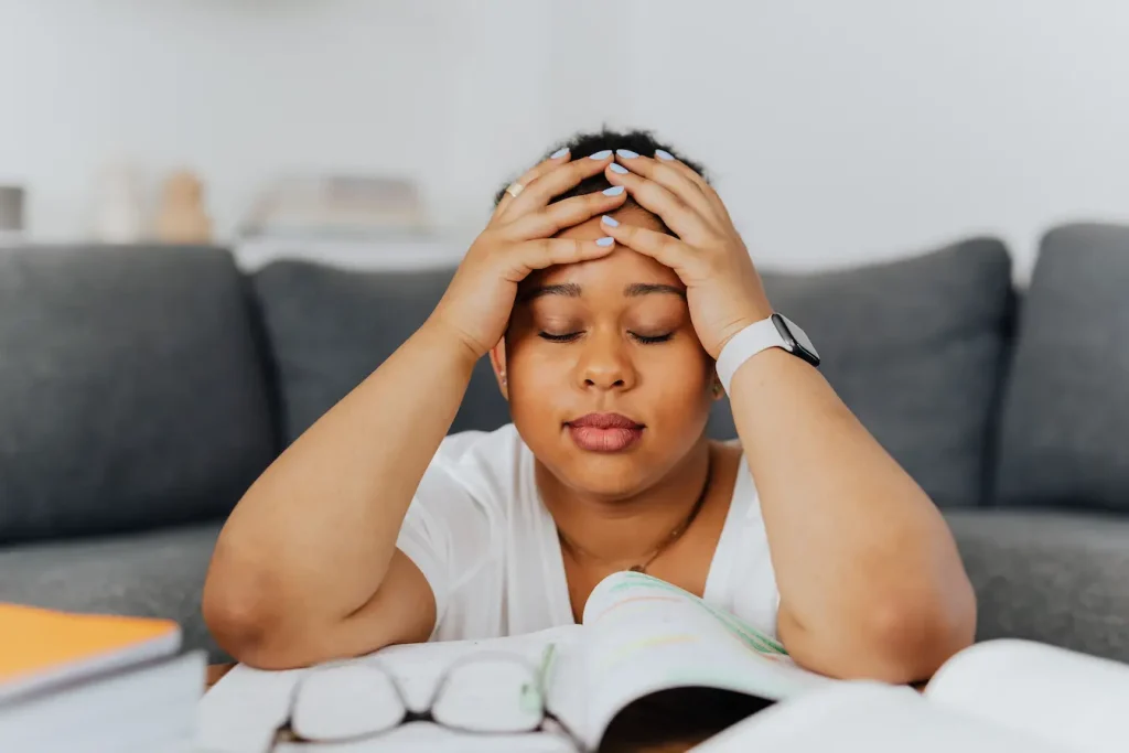Personne assise la tête dans les mains devant cahiers, image qui illustre réduire le stress grâce aux bienfaits de la gelée royale.