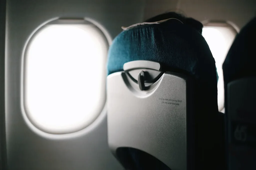 Vue rapprochée sur siège d’avion et hublot lumineux, reflet des causes des jambes qui gonflent en avion et solutions pour les prévenir.