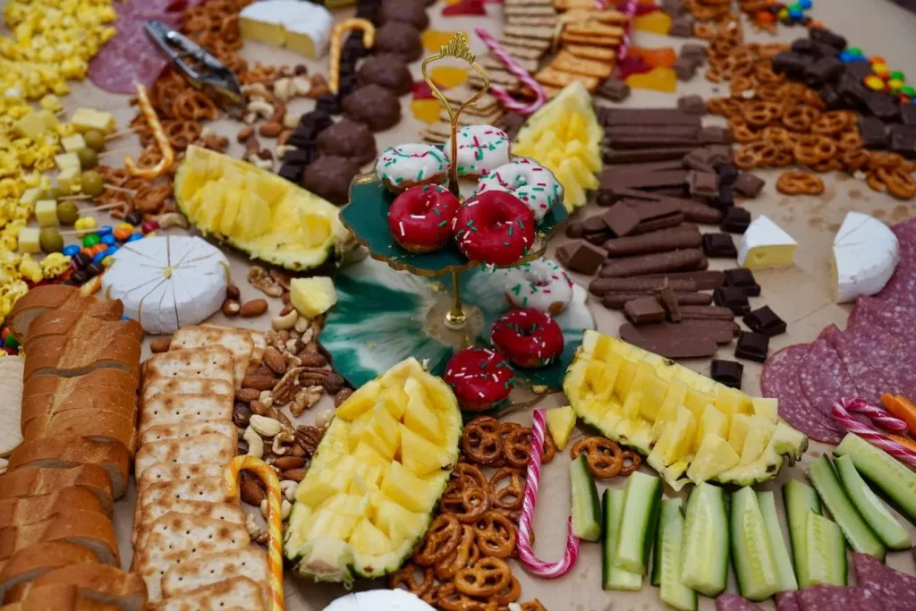 Grande table garnie de fromages, charcuterie, fruits et sucreries, reflet des aliments déclencheurs possibles de migraine à identifier.