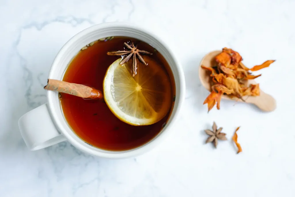 Tasse de thé chaud avec citron, cannelle et anis étoilé, image qui illustre les aliments riches en mélatonine naturelle pour favoriser le sommeil.