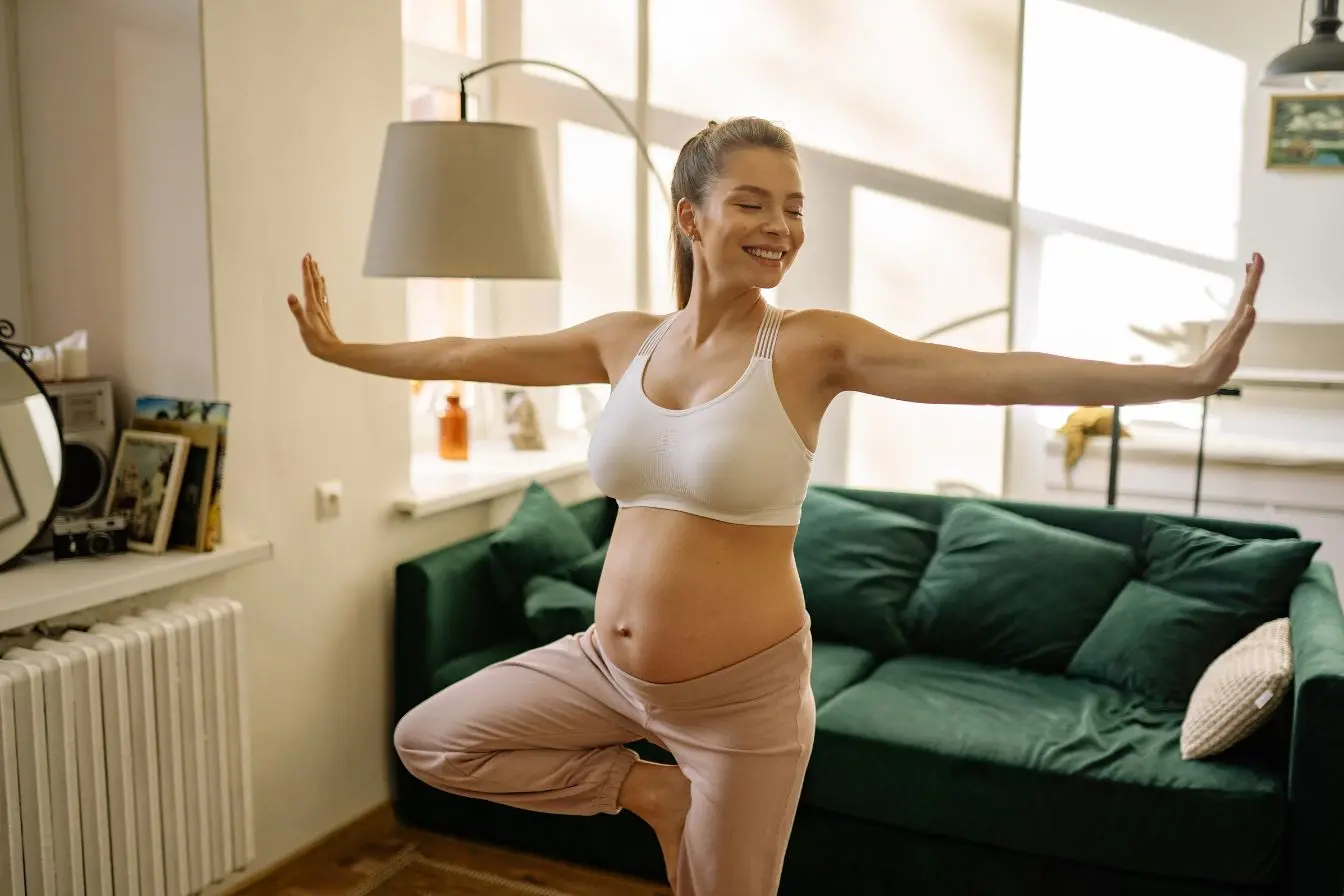Femme enceinte en tenue sportive réalisant posture de yoga, symbole des pratiques naturelles pour prévenir les vergetures.