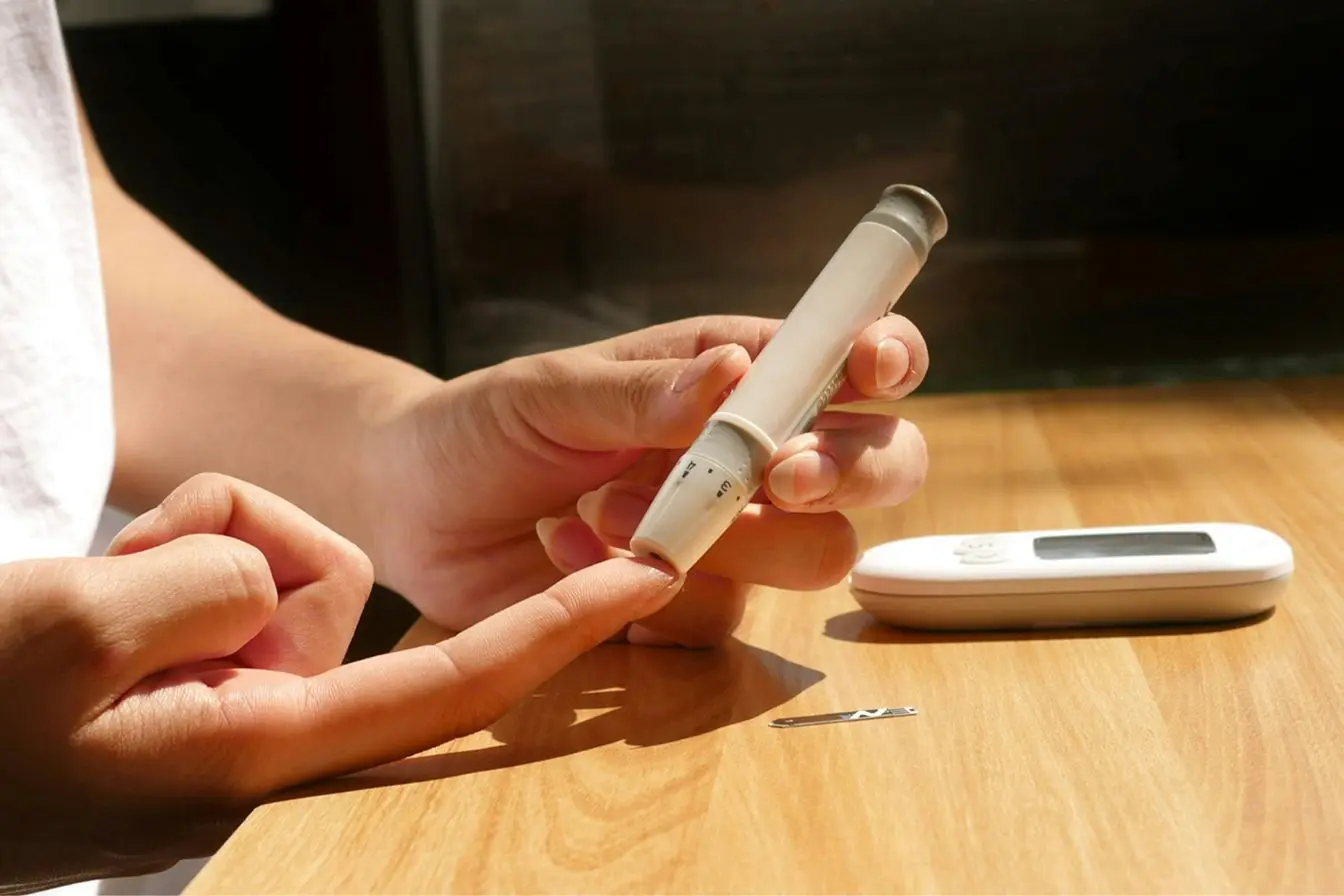 Mesure de la glycémie Une personne utilise un stylo piqueur sur son doigt pour mesurer sa glycémie et réagir face à une hypoglycémie.