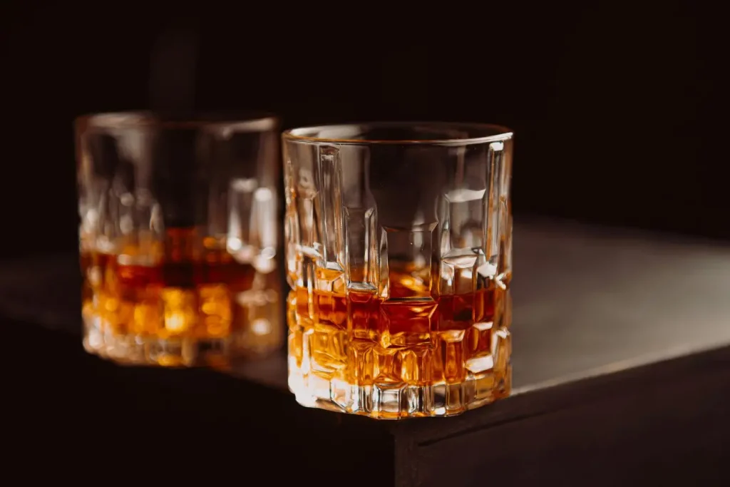 Deux verres de spiritueux posés sur une table sombre, une image qui évoque l’impact possible de la consommation d’alcool sur la libido masculine