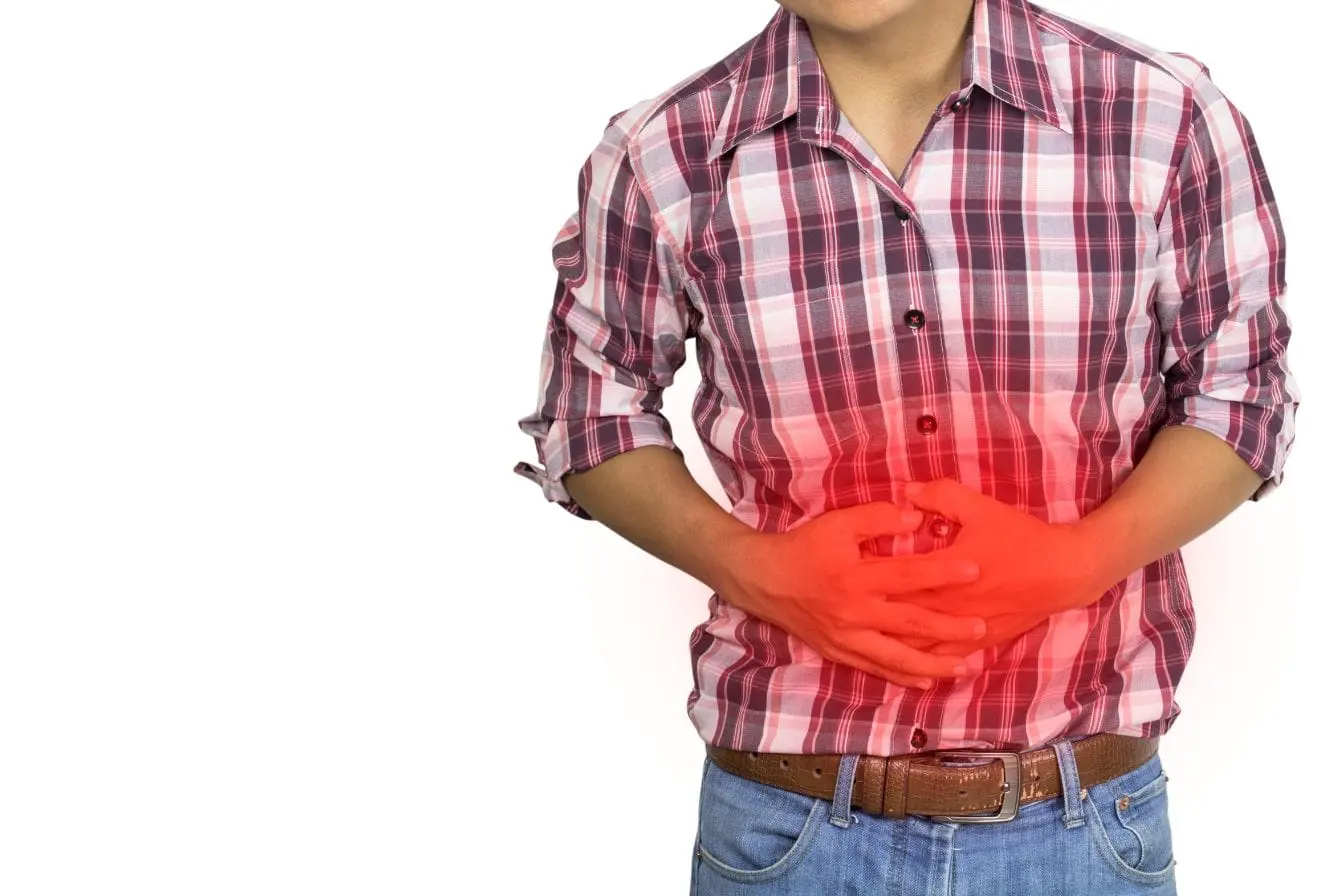 Personne en chemise à carreaux tenant son ventre avec douleur, symbole des brûlures d’estomac liées au reflux gastrique.