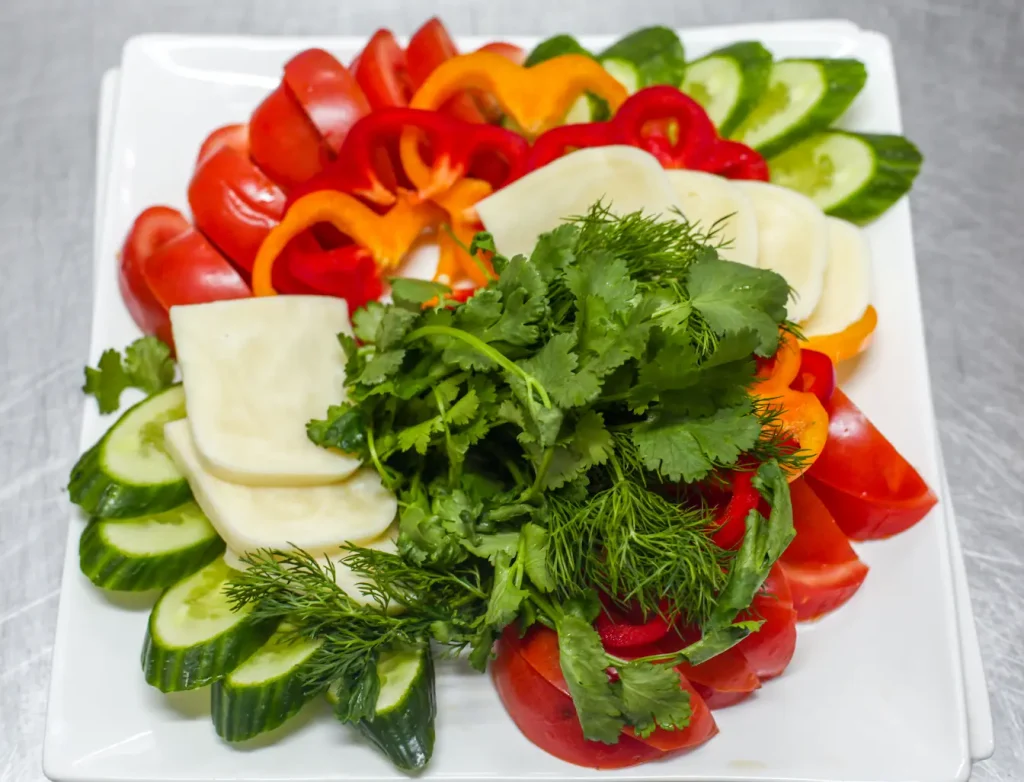 Assiette carrée avec légumes frais et herbes, symbole d’une alimentation équilibrée pour limiter les poussées de rosacée.
